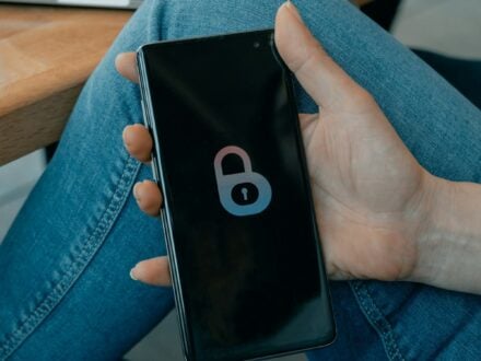 A hand holding a smartphone that displays a large padlock icon on its lock screen