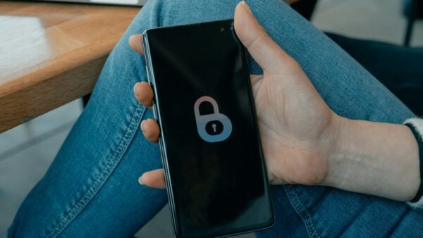 A hand holding a smartphone that displays a large padlock icon on its lock screen